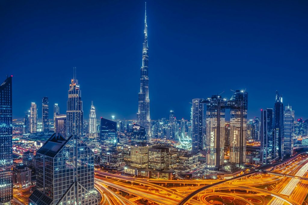 The Burj Khalifa towering over the illuminated Dubai skyline at night with busy highways